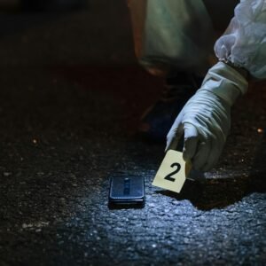 Forensic investigator examining evidence in a city street at night.